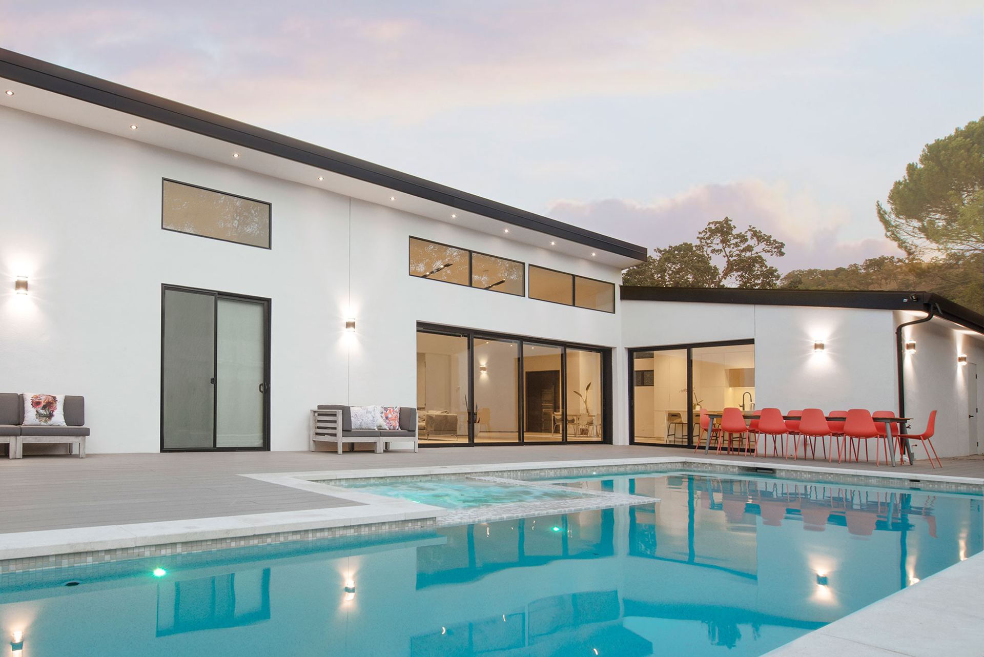 Modern single-story home with pool at dusk