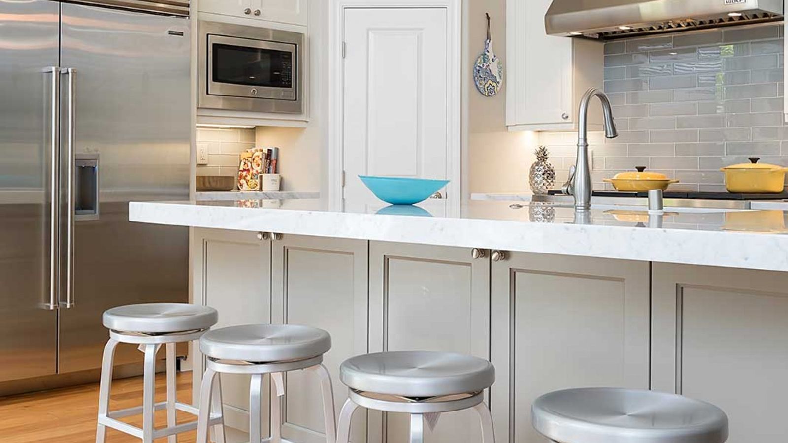 White kitchen with marble bar counter and metal stools