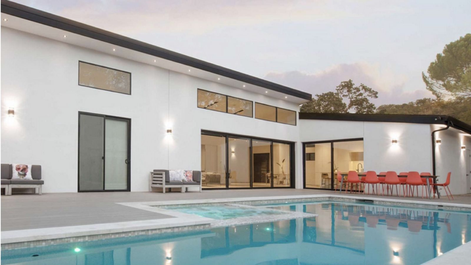 Modern home with pool and outdoor dining at dusk
